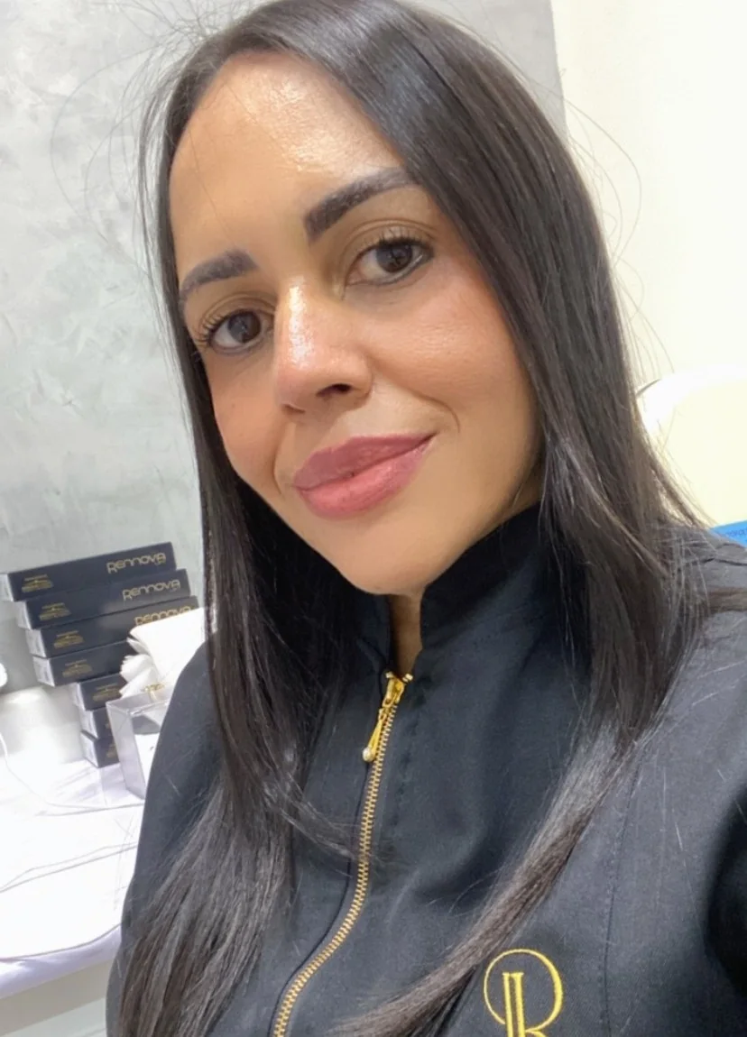 Dra. Leila Rodrigues sorrindo, com o jaleco preto bordado com o monograma LR em dourado