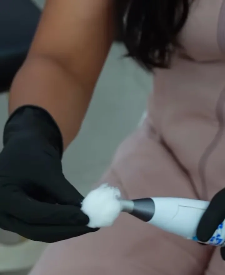 Aparelho de laserterapia sendo aplicado com luvas pretas
