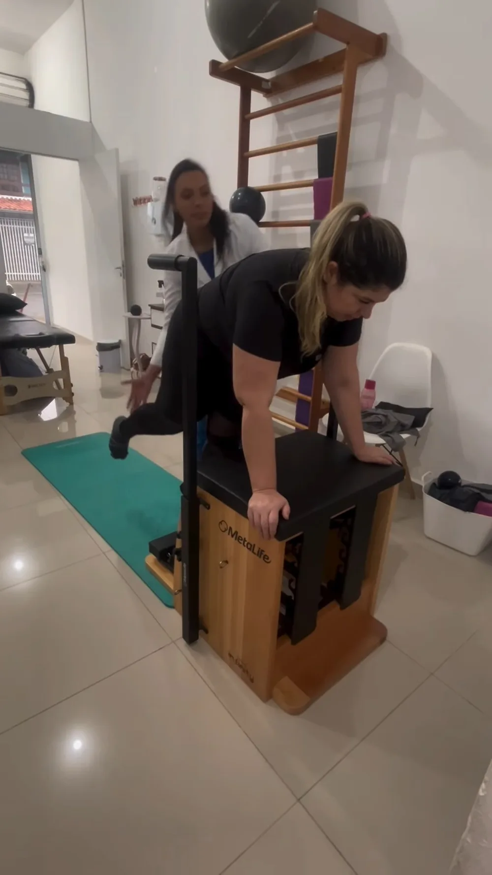 Paciente fazendo exercício de pilates na chair com a fisioterapeuta acompanhando