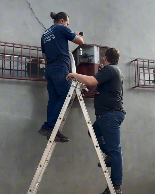 Técnico na escada fazendo manutenção de ar condicionado