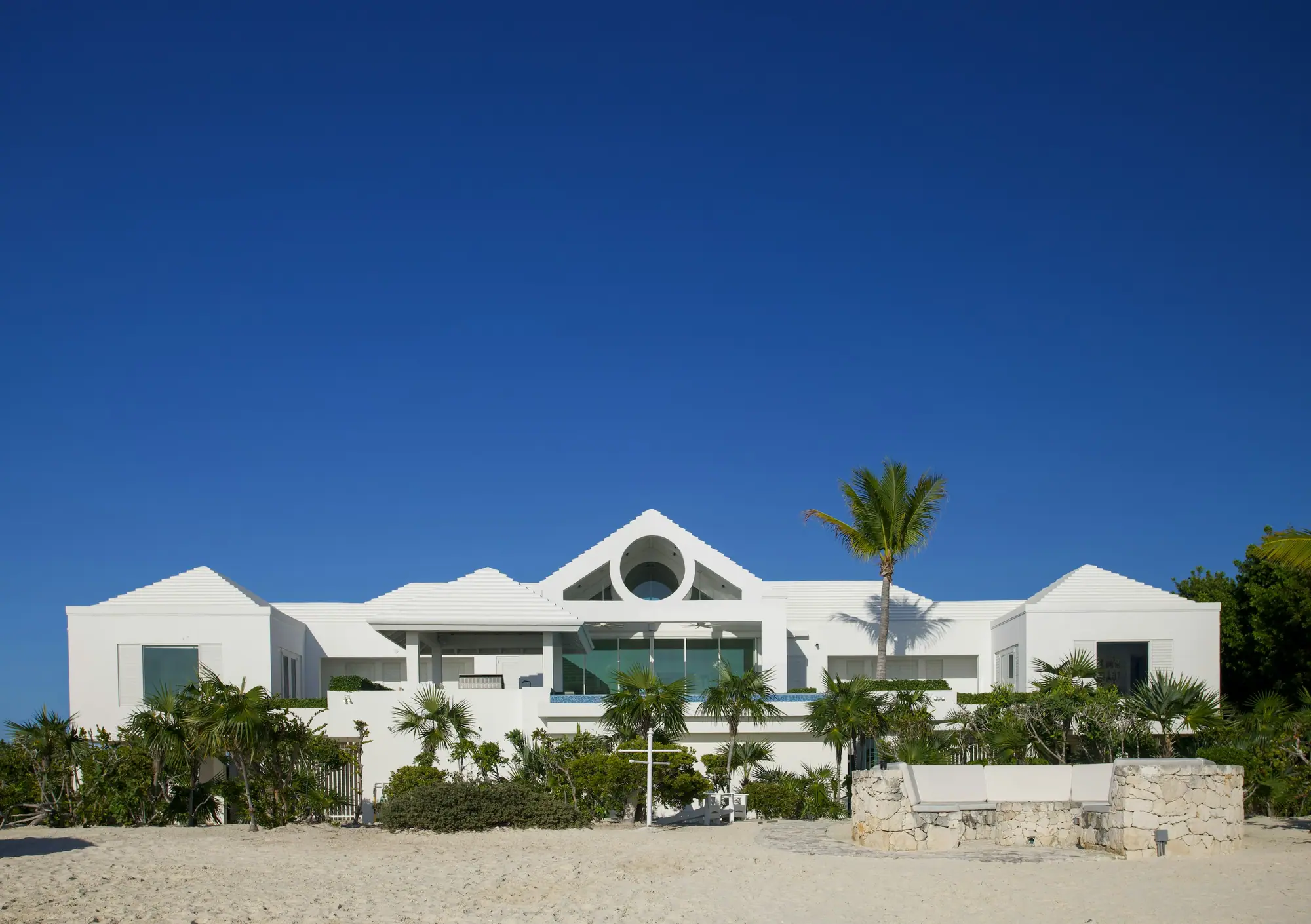 Casa branca de linhas contemporâneas entre palmeiras