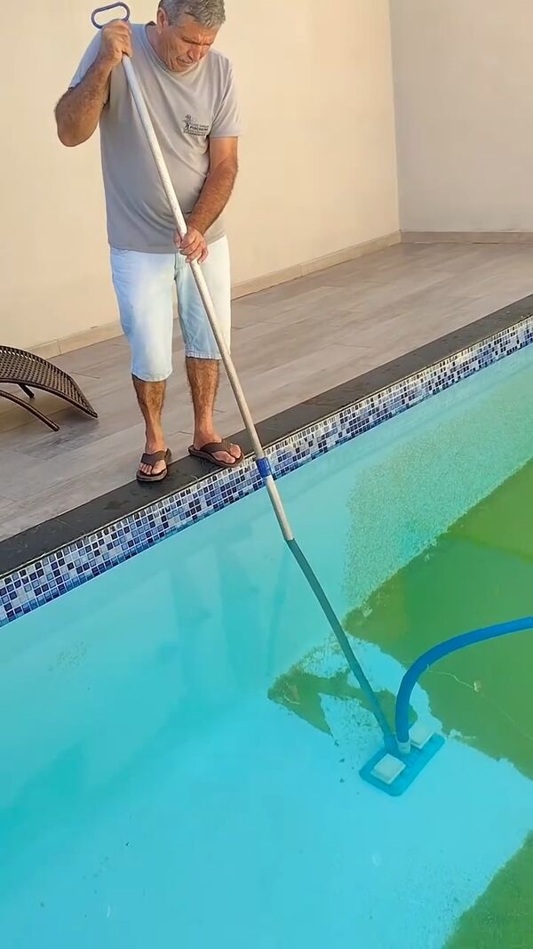 Pessoa aspirando a própria piscina em casa