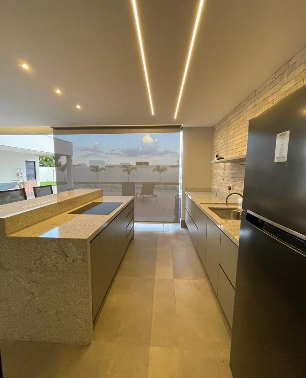 Cozinha integrada à varanda com ilha em granito claro e iluminação de LED